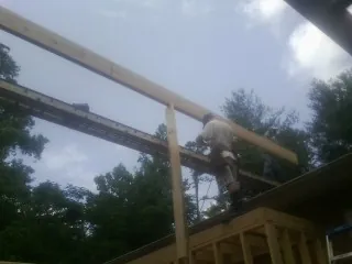 Carpenter setting a ridge beam over a new addition frame — Ice Dam Removal by Roofing Brothers in Weirsdale