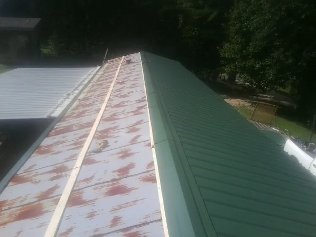 Old rusted panels beside newly installed green metal roofing — Wind Damage Roof Repair by Roofing Brothers in Weirsdale