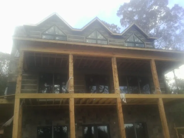 Dormers and porch framing on a large log home under construction — Roof Coating work by our crew in Weirsdale