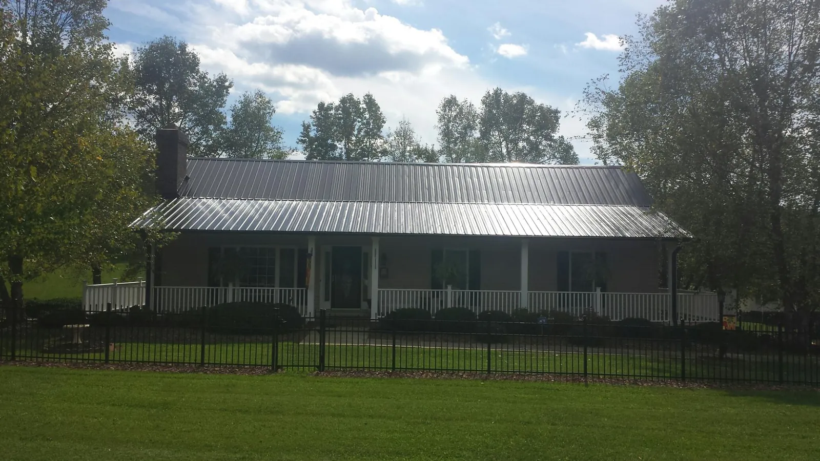 Gray metal roof on a brick ranch with a full width front porch — Gutter Guard Installation work by our crew in Weirsdale