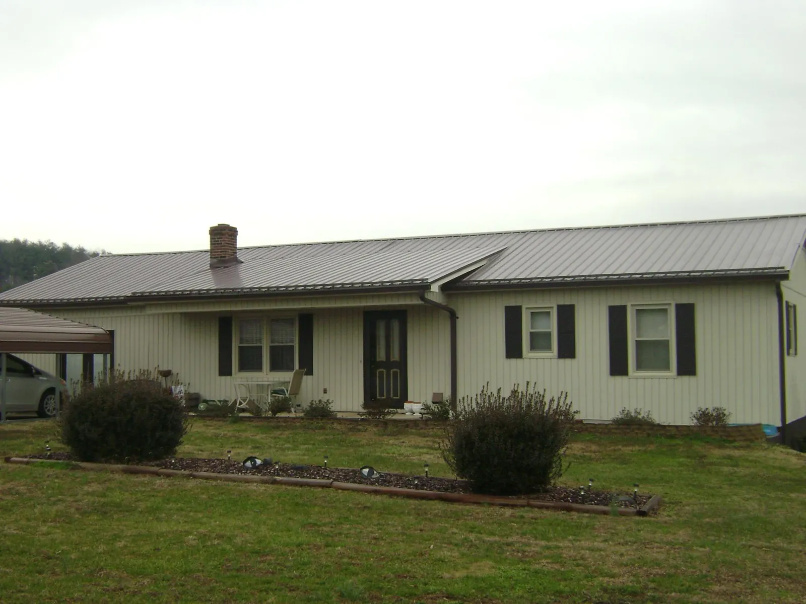 Brown metal roof on a cream sided ranch home with a brick chimney in Weirsdale