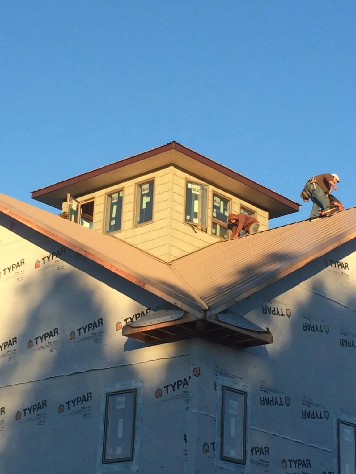 Roofers working around a rooftop cupola on a new metal roof at sunset — Roof Waterproofing in Weirsdale by Roofing Brothers